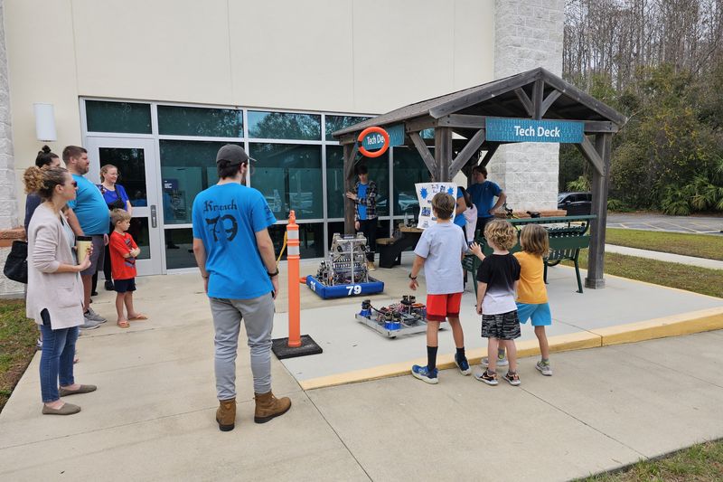 Team 79 Krunch members demonstrating their robot to families at a community library event