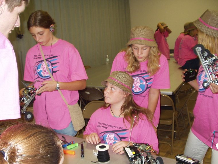 Girls in FIRST shirts building a robot at a girls-only STEM workshop