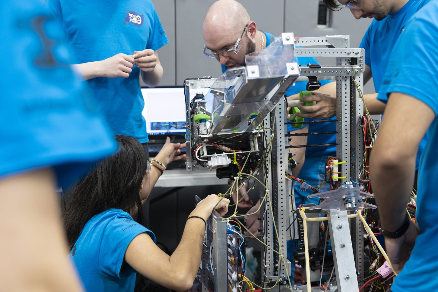 A Team 79 Krunch mentor and students working together on the competition robot in the pit