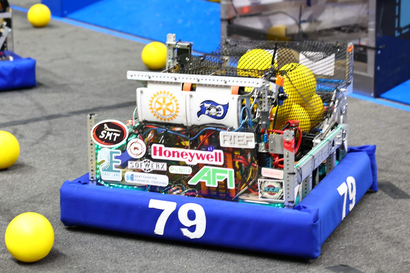 Team 79 Krunch's robot on the competition field, its panel covered in sponsor logos including Honeywell, AFI, SMT, Publix, SOFWERX, and Rotary