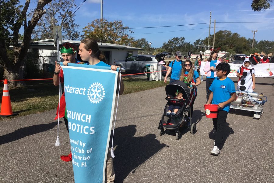Team 79 Krunch carrying the Rotary Interact banner and their robot in the Palm Harbor Holiday Parade